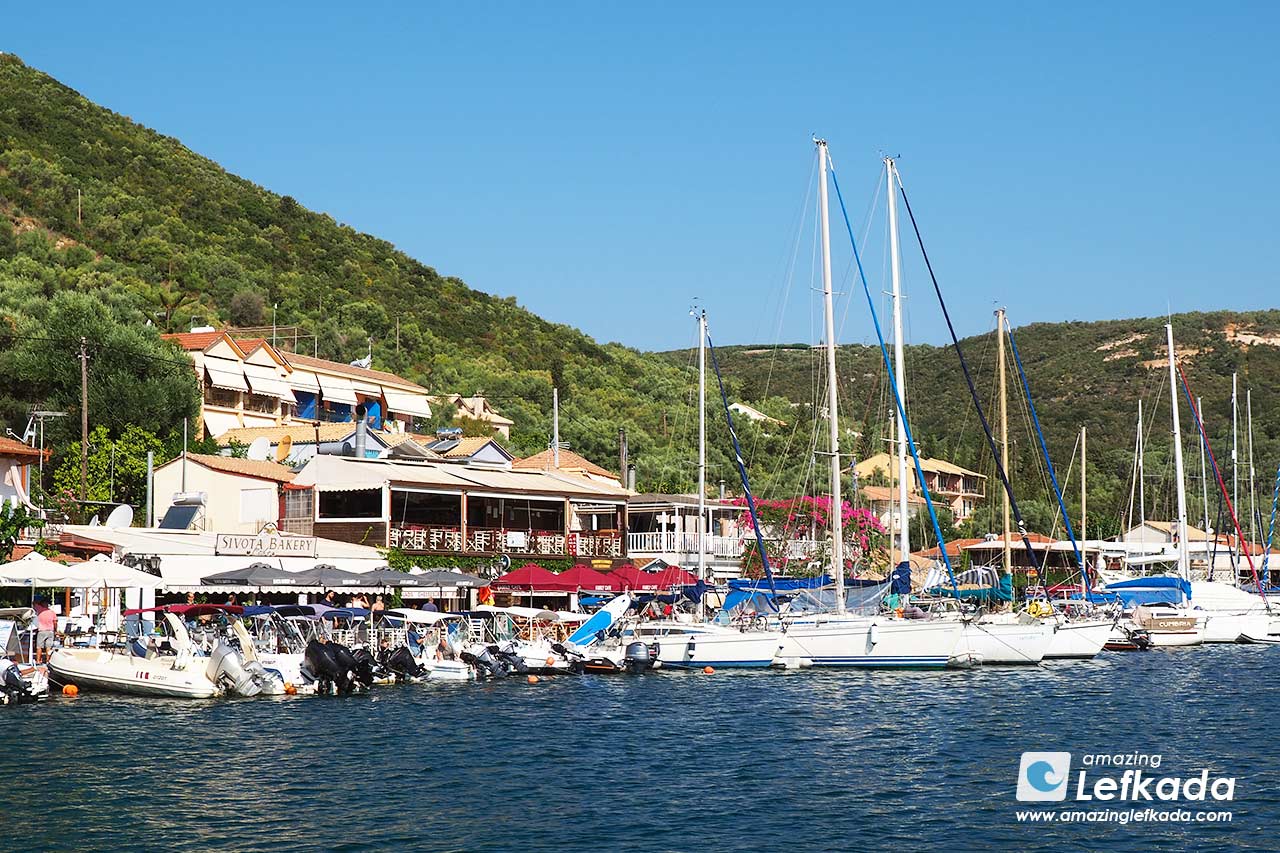 Houses of Sivota village with boats in a port