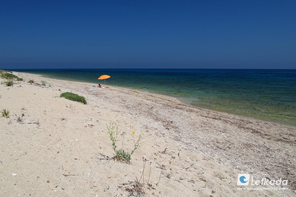 Secluded part of Lefkada Island at Kastro beach with a parasol and shallow blue sea Secluded part of Lefkada Island at Kastro beach