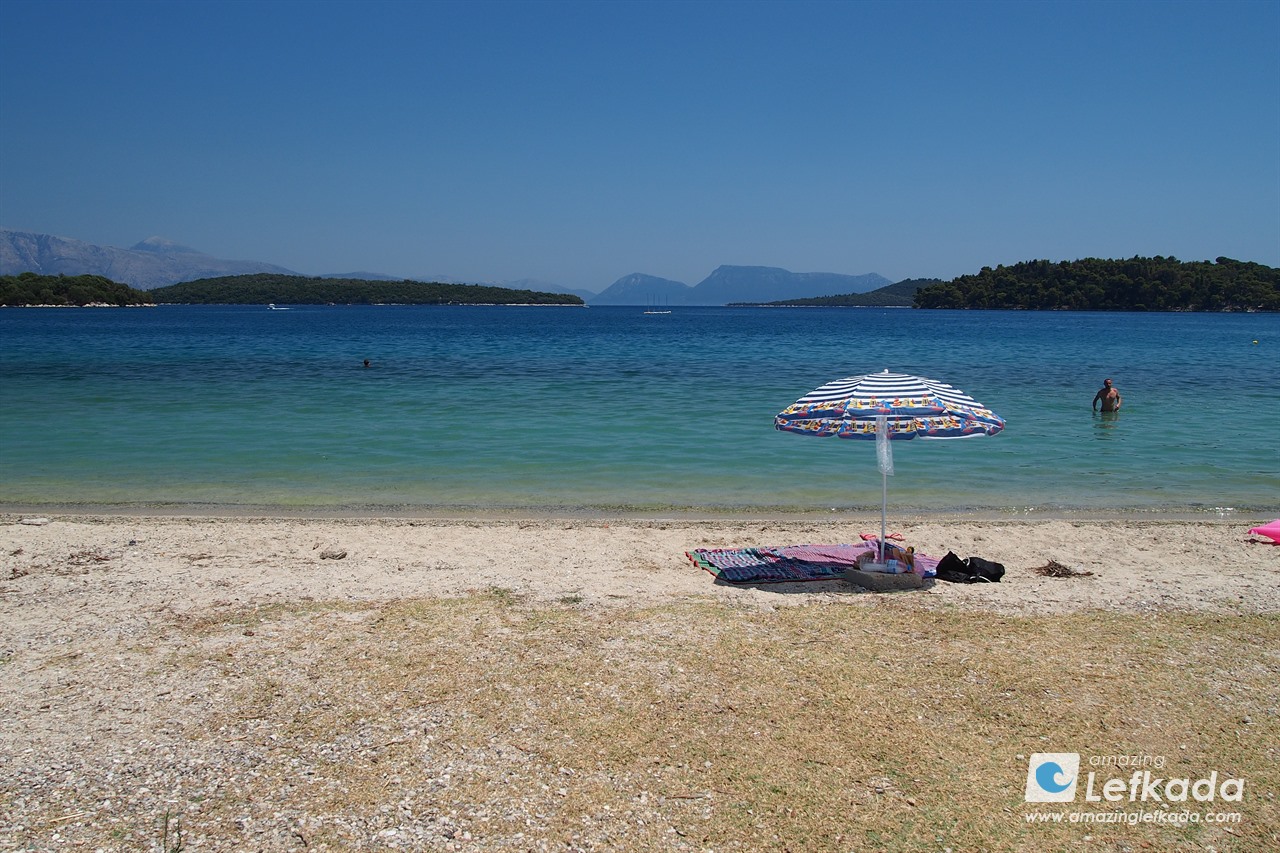 Coarse sand and shallow sea at Paralia Nidri beach in Lefkada Island Coarse sand and shallow sea at Paralia Nidri beach in Lefkada Island with sunbeds
