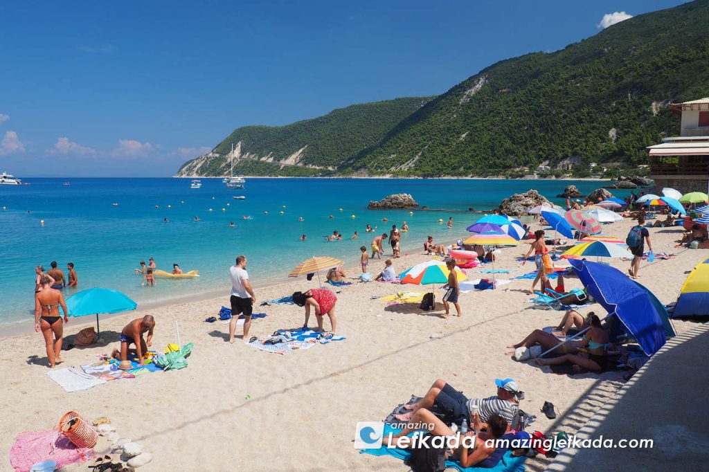 Vacationers of Agios Nikitas beach with parasols and sunbeds in Lefkada Island